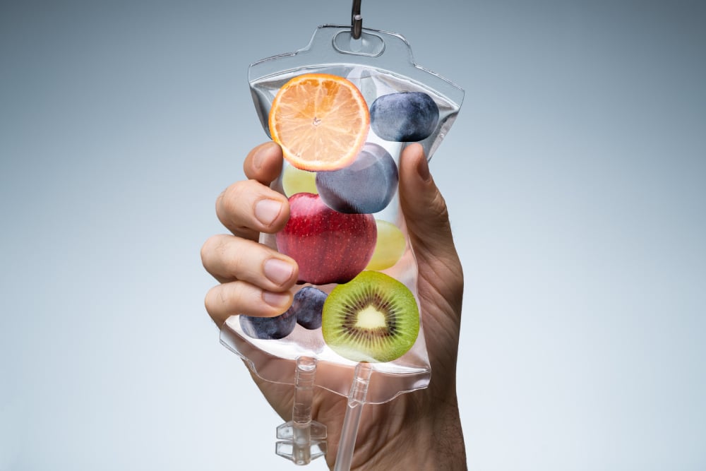 A close-up shot of someone holding an IV bag filled with different fruits