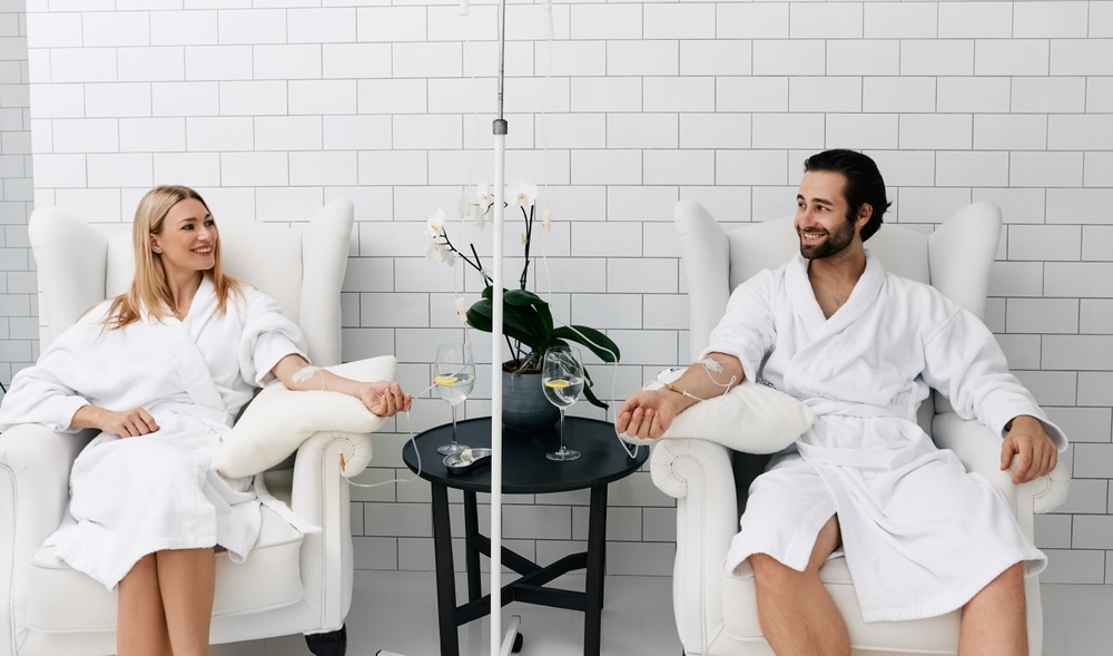 Man and woman happy smiling while receiving their wellness IV therapy.